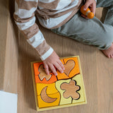 A child playing with the Grimm's Building Set in Yellow. Wooden blocks in various shades of yellow and natural wood in a yellow coloured wooden storage tray. These Grimm's toys are part of a wide range of wooden toys available here at Babipur. 