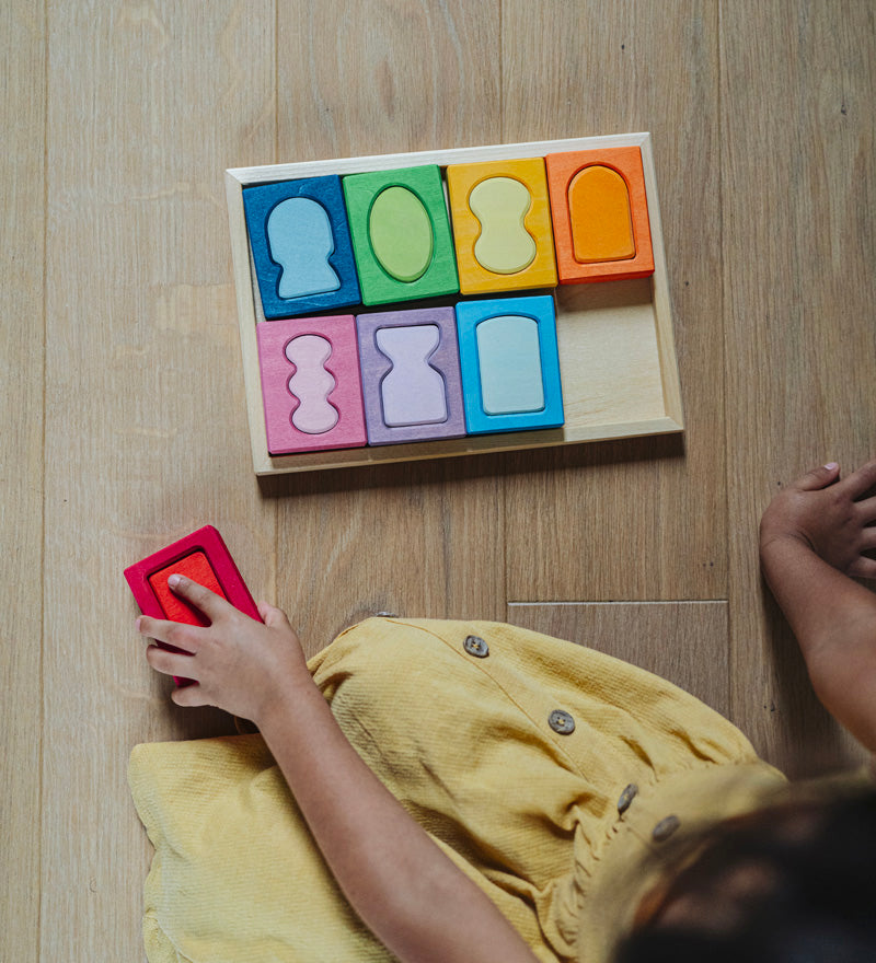 An overhead view of a child with the Grimm's windows building set blocks set on the floor in front of them. These Grimm's toys are part of a wide range of wooden toys available here at Babipur. 