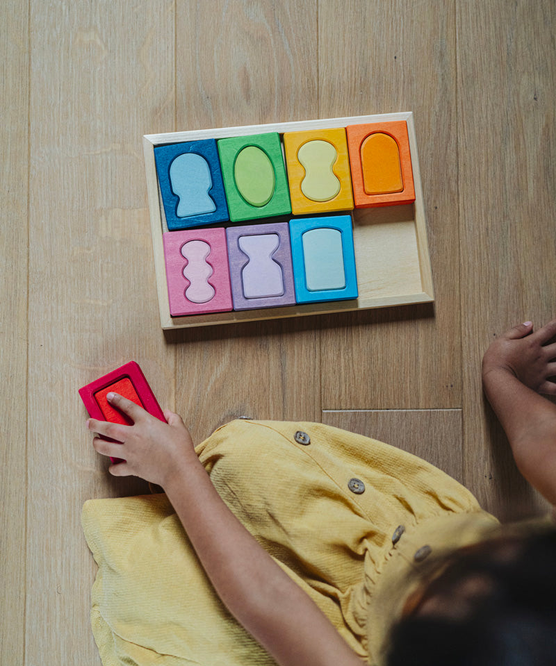 An overhead view of a child with the Grimm's windows building set blocks set on the floor in front of them. These Grimm's toys are part of a wide range of wooden toys available here at Babipur. 