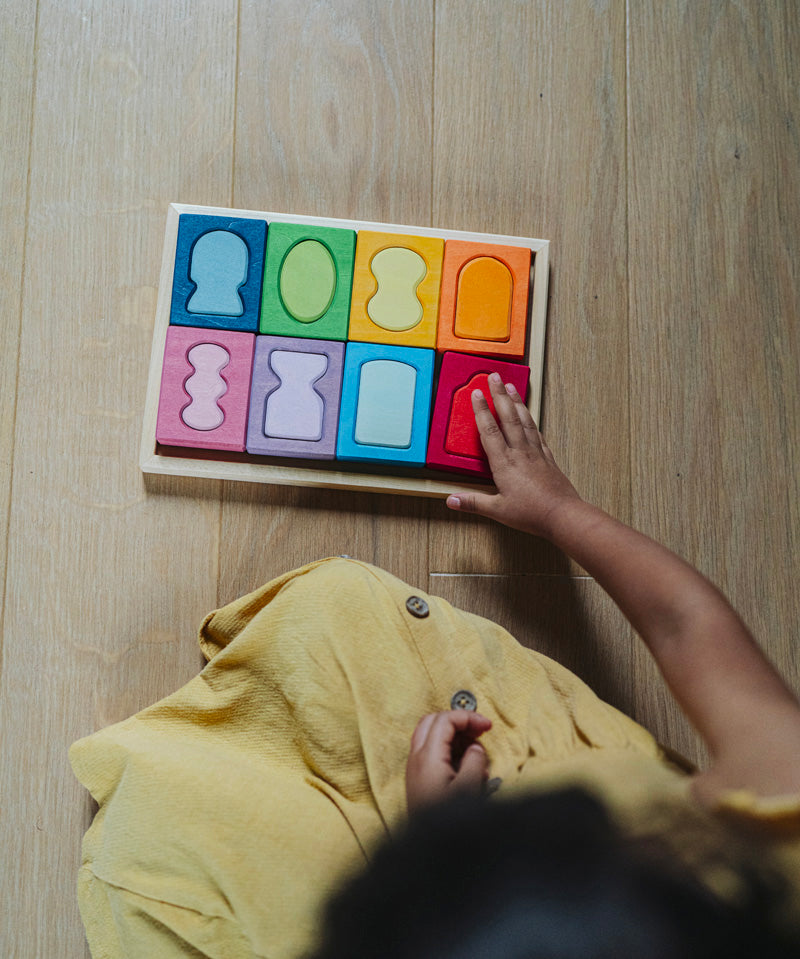 An overhead view of a child with the Grimm's windows building set blocks set on the floor in front of them. These Grimm's toys are part of a wide range of wooden toys available here at Babipur. 