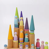 Grimm's large wooden building rollers in natural in a tray with pastel friends and forest pieces placed on top of them.