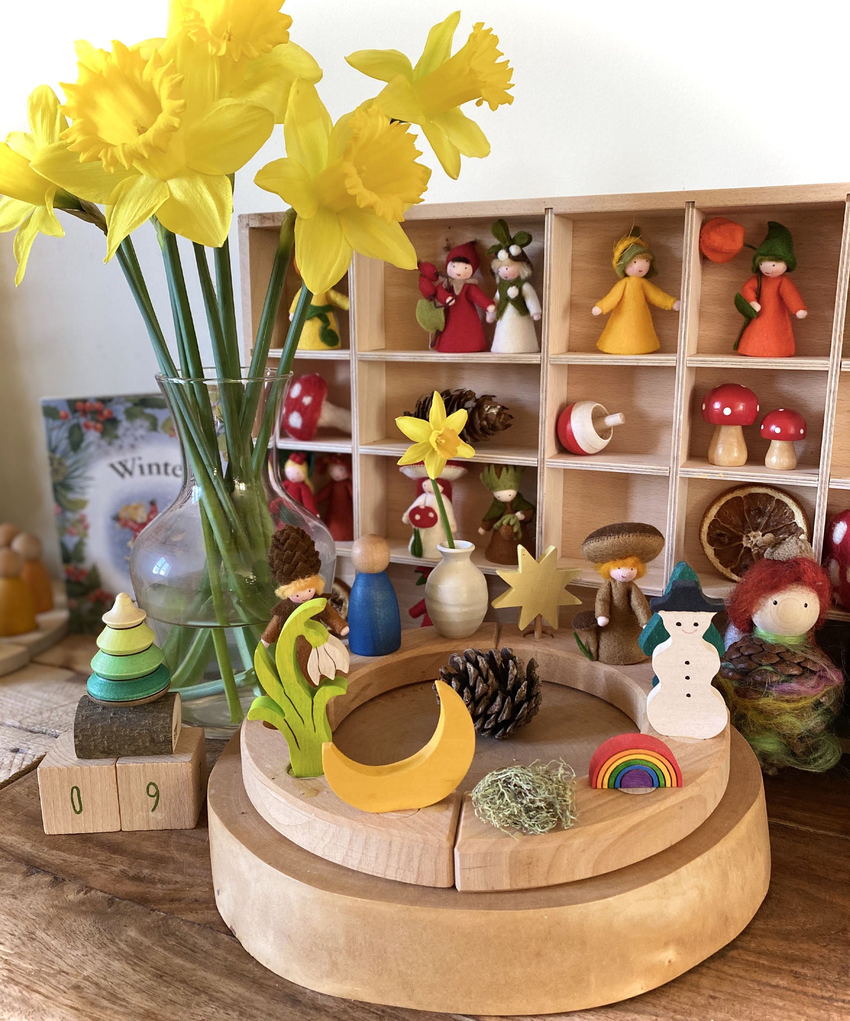 A bright and cheerful inspired calendar display using a Grimm's 12 hole Waldorf Celebration Ring, Grimm's decorative figures and a Ambrosius doll available at Babipur.