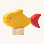 A close up of the Grimms wooden yellow fish decorative figure with red fins. Showing the hand painted detail and thickness of the figure