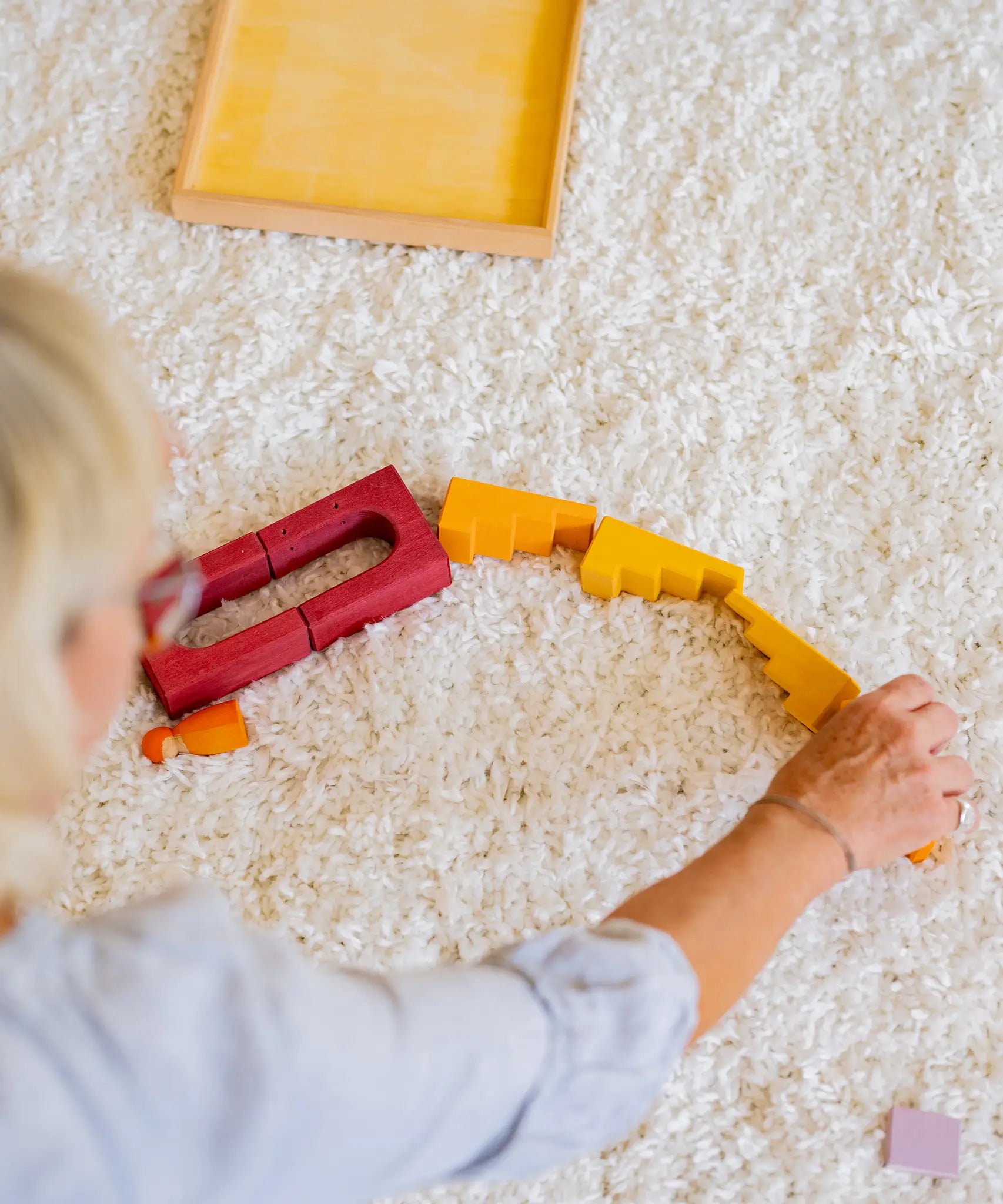 Woman placing loose Grimms desert sand wooden blocks in a line