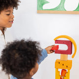 Child holding a wooden block from the Grimms desert sand building set on a tower showing scale