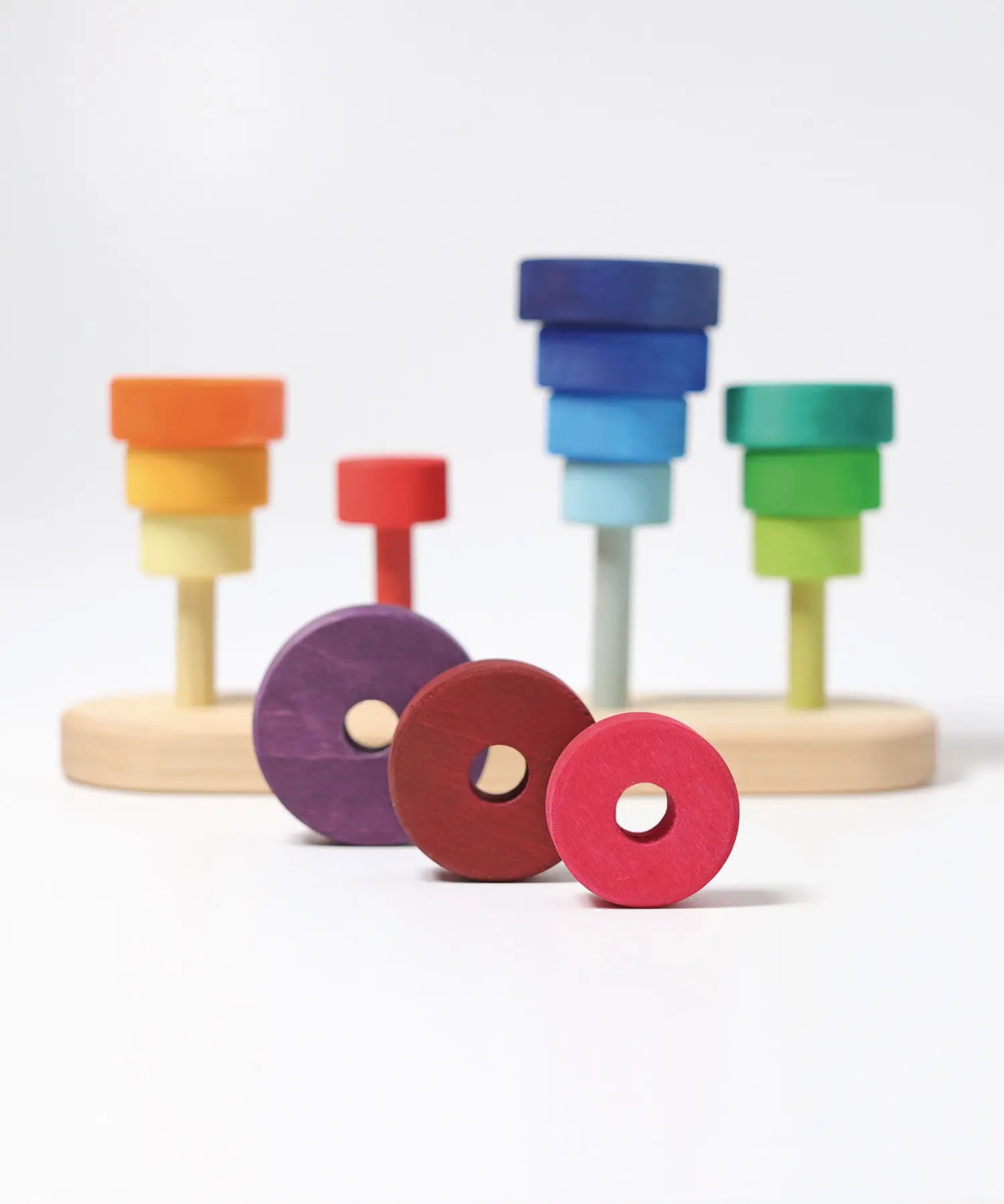 3 loose disks in dark red and purple with holes from the Grimms fabuto set in front of the stacking base