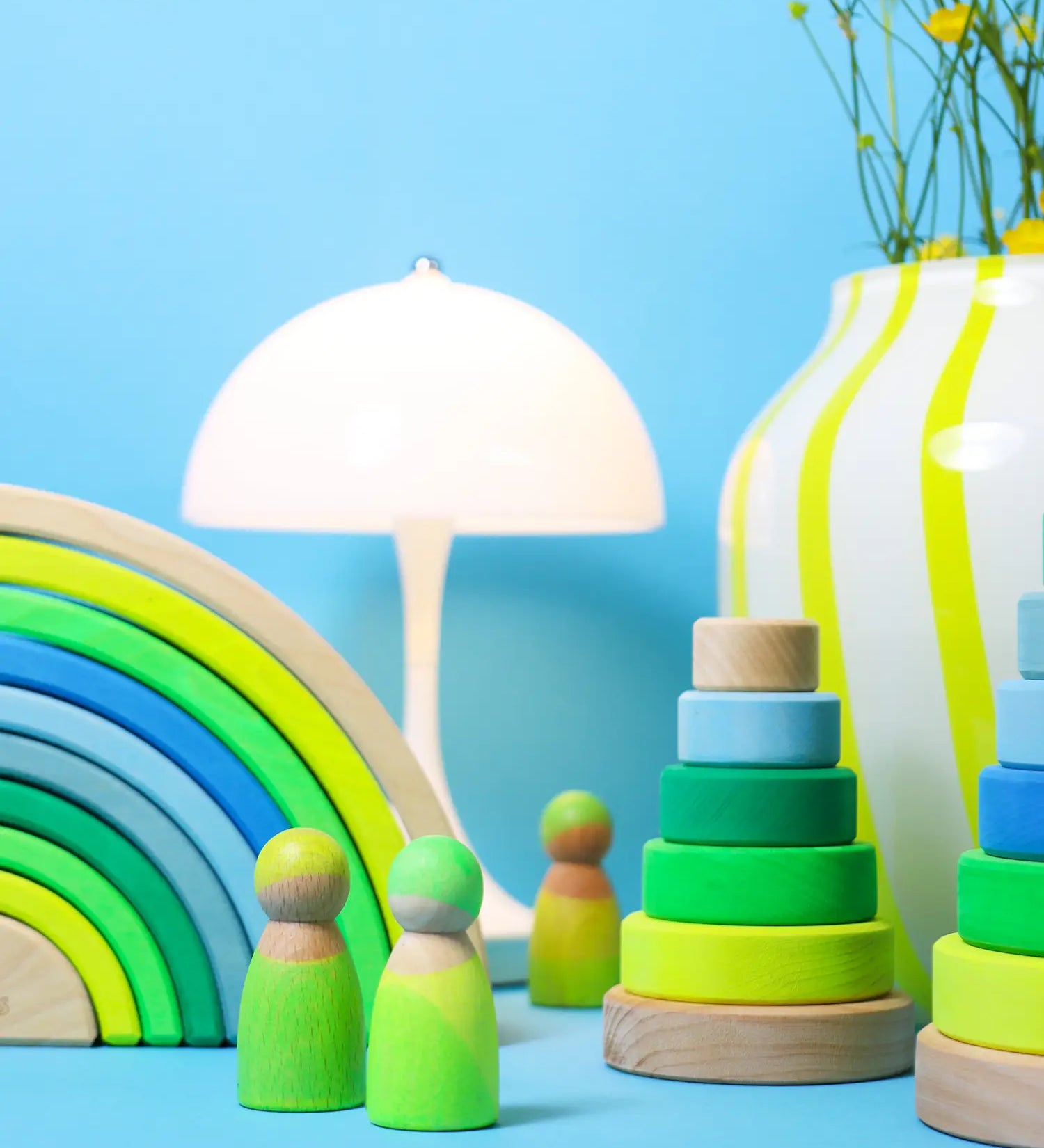A play scene using the Grimms neon green rainbow, peg dolls and stacking towers