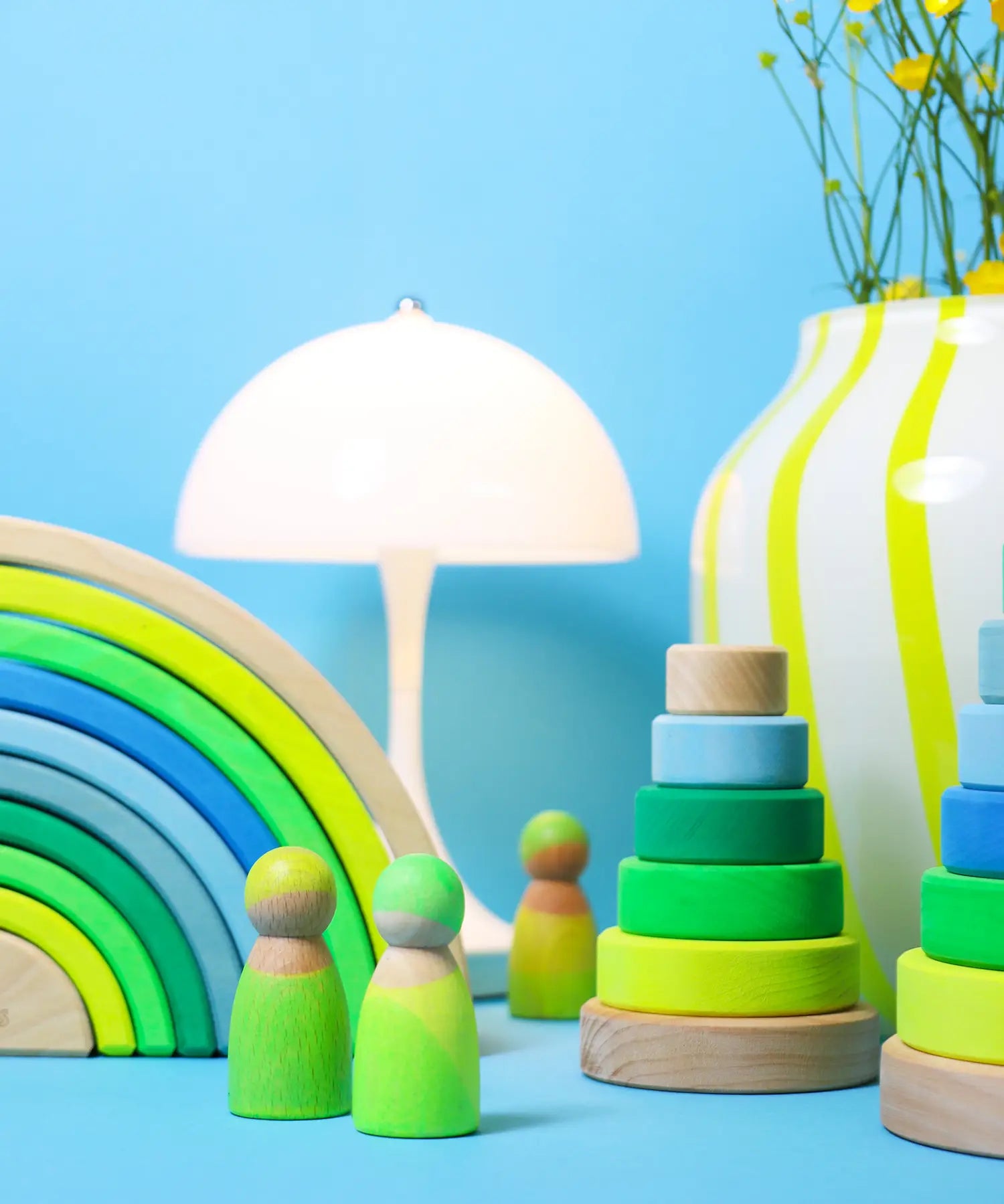 A play scene using the Grimms neon green rainbow, peg dolls and stacking towers