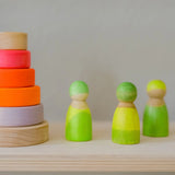 Grimms handcrafted wooden neon green peg dolls next to a small neon pink stacking tower
