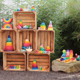 Collection of Grimm's wooden toys displayed outdoors on wooden crates. 