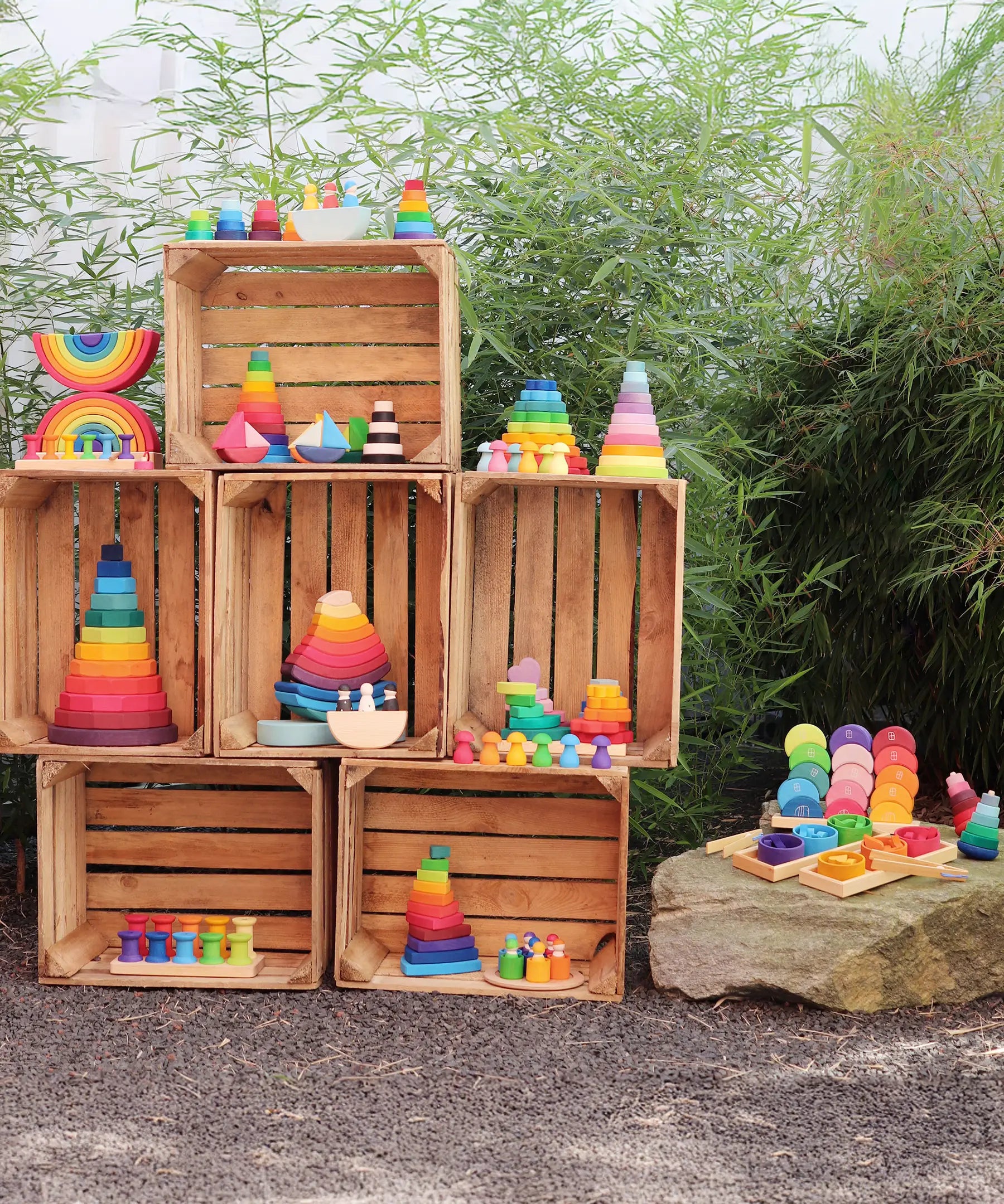 Collection of Grimm's wooden toys displayed outdoors on wooden crates. 