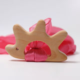 A Grimm's Hedgehog shaped wooden grasping toy with a piece of pink ribbon material attached. 