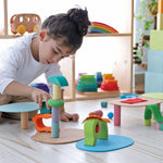 Close up of a Grimm's Friend peg doll figure leaning on a green wooden Waldorf toy block in front of a green rainbow toy