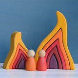 Grimm's handcrafted wooden large fire set standing next to a smaller set and 2 peg dolls for scale