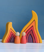Grimm's handcrafted wooden large fire set standing next to a smaller set and 2 peg dolls for scale