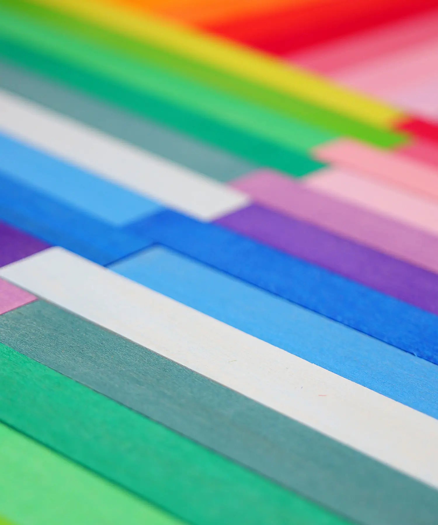 Grimm's handcrafted wooden Leonardo sticks laid flat showing the hand dipped pastel and rainbow colours on the sticks