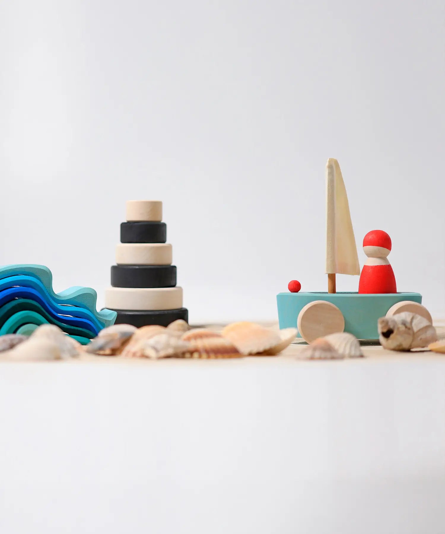 Grimms' handcrafted wooden little land yacht standing next to a monochrome stacking tower and wave set