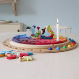 A display using a Grimms circular disk, rainbow marbles and decorative figures. 