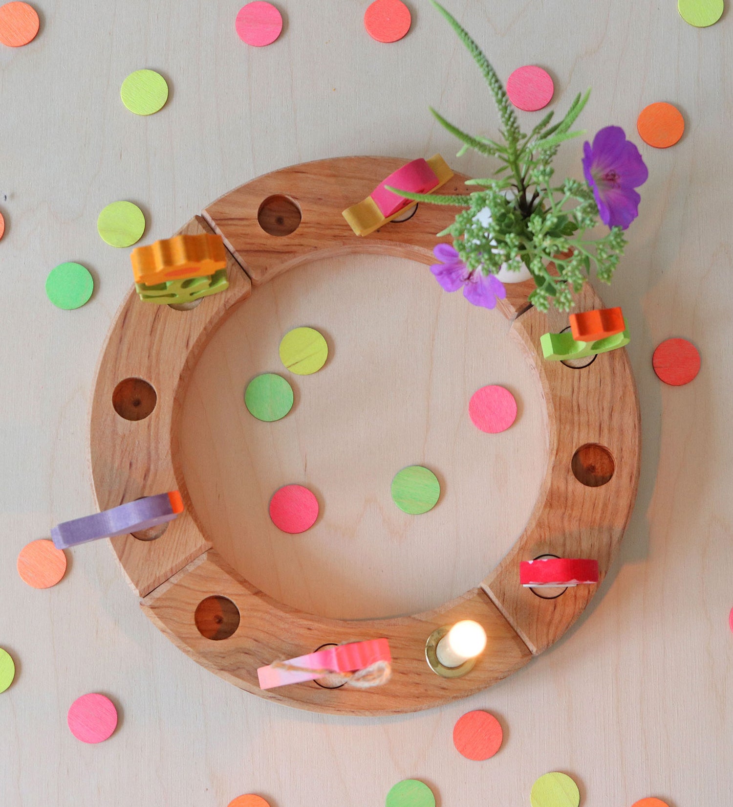 Grimm's Neon Celebration Confetti Dots. The dots surround a celebration ring on a wooden table.