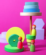 Grimms wooden friends in a hand painted neon mix finish standing next to a neon green conical tower 
