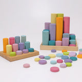 Loose Grimms wooden coins next to cylinder roller stacking sets all in a pastel palette
