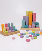 Loose Grimms wooden coins next to cylinder roller stacking sets all in a pastel palette