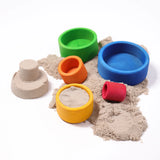 Grimms brightly coloured wooden bowls with sand inside next to a small sandcastle 