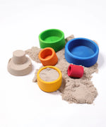 Grimms brightly coloured wooden bowls with sand inside next to a small sandcastle 