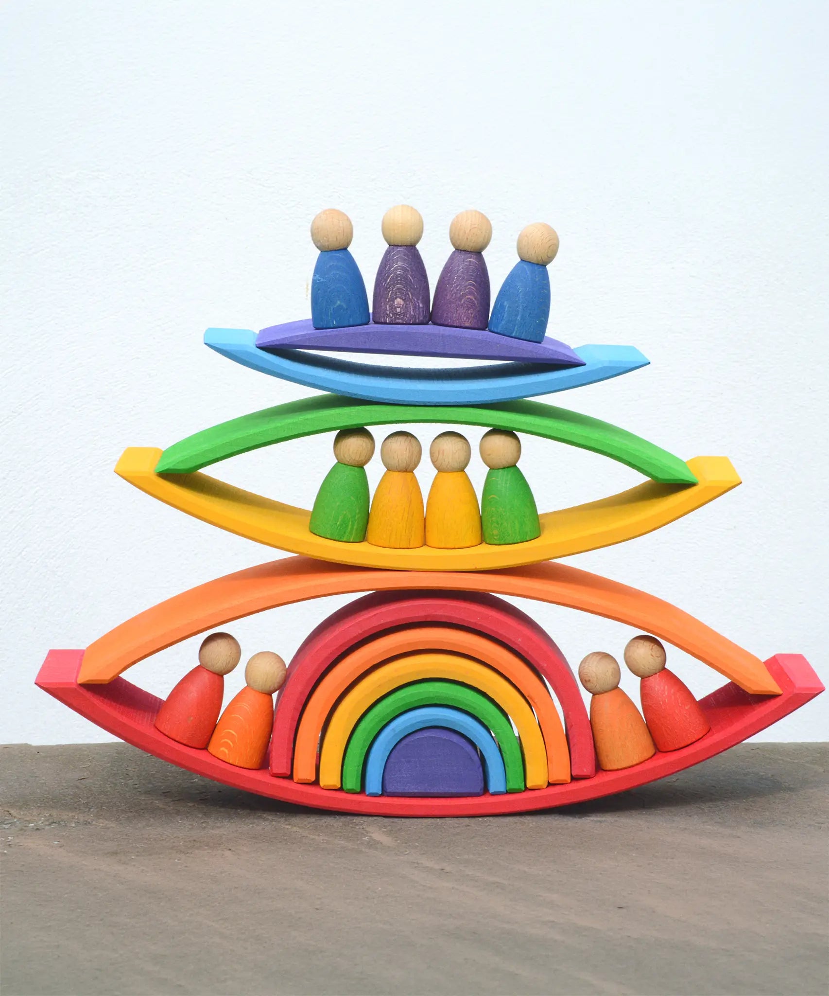 Grimms handcrafted wooden rainbow bridges stacked with peg dolls in between 