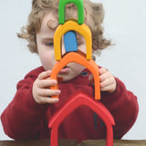 Child stacking the Grimm's house shaped pieces in a rainbow palette