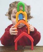 Child stacking the Grimm's house shaped pieces in a rainbow palette