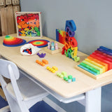 Grimm's wooden toys placed on a desk. Handmade and hand painted rainbow coloured toys