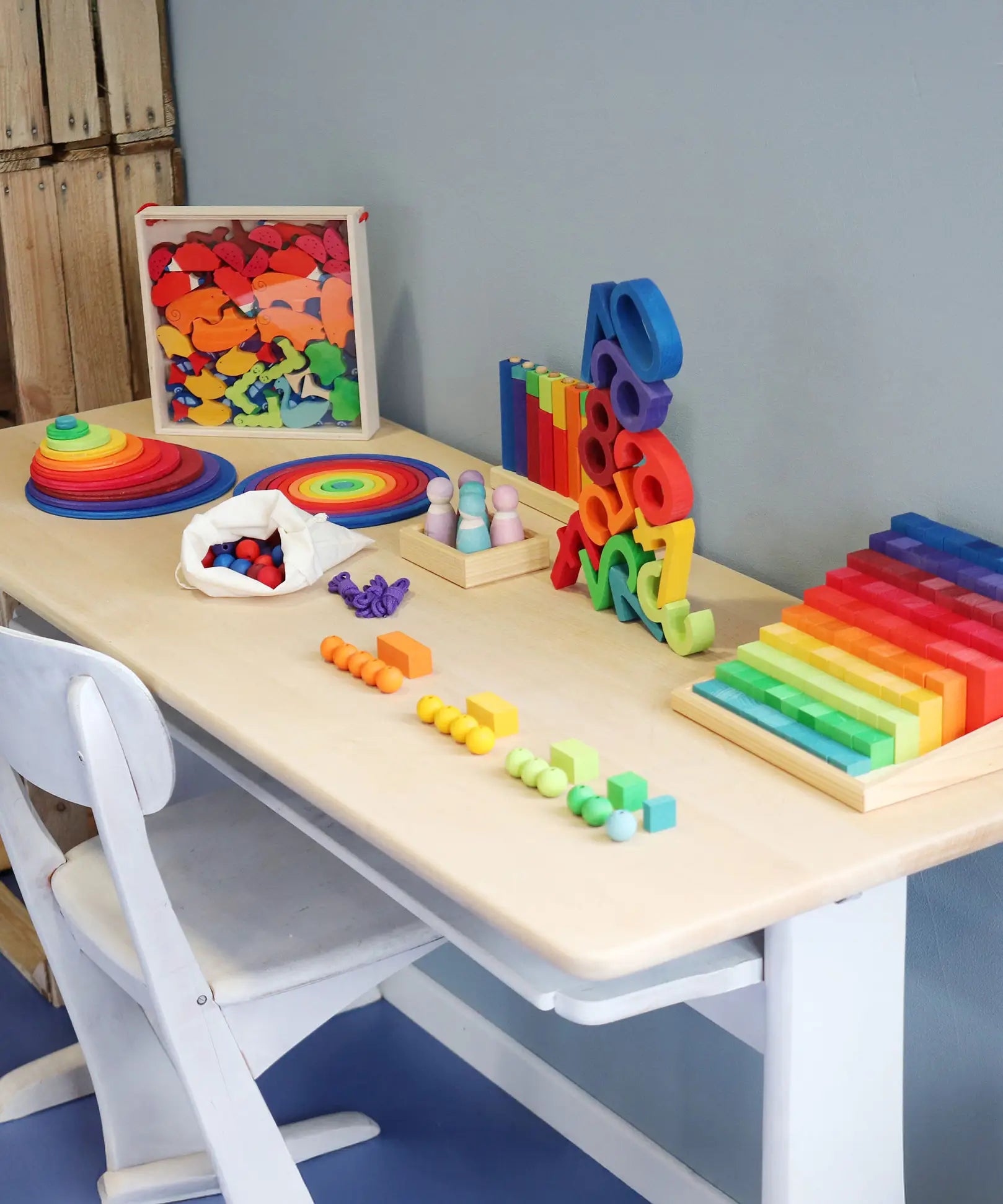 Grimm's wooden toys placed on a desk. Handmade and hand painted rainbow coloured toys