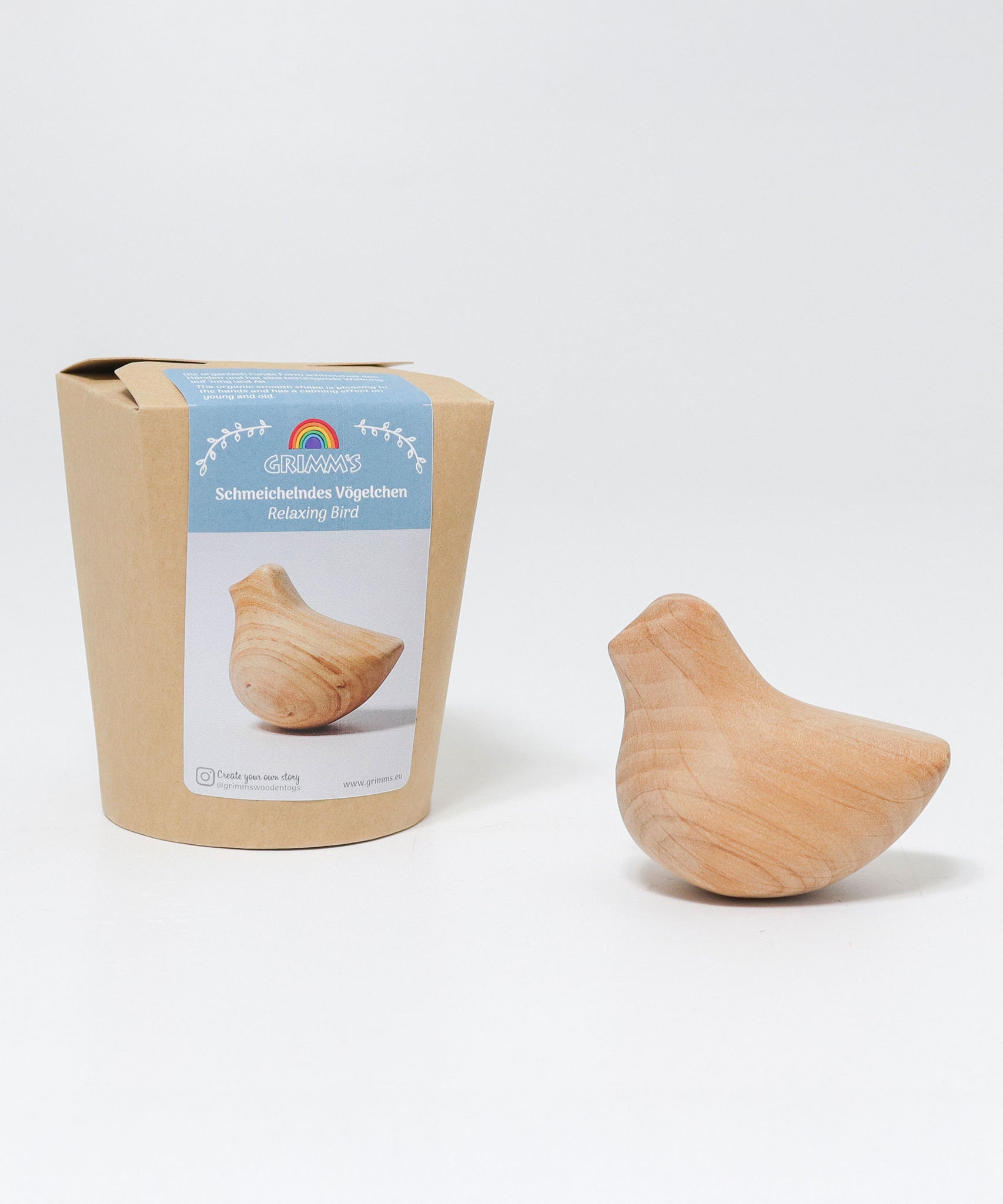 The Grimm's wooden relaxing bird toy shown next to it's plastic free, cardboard packaging box.