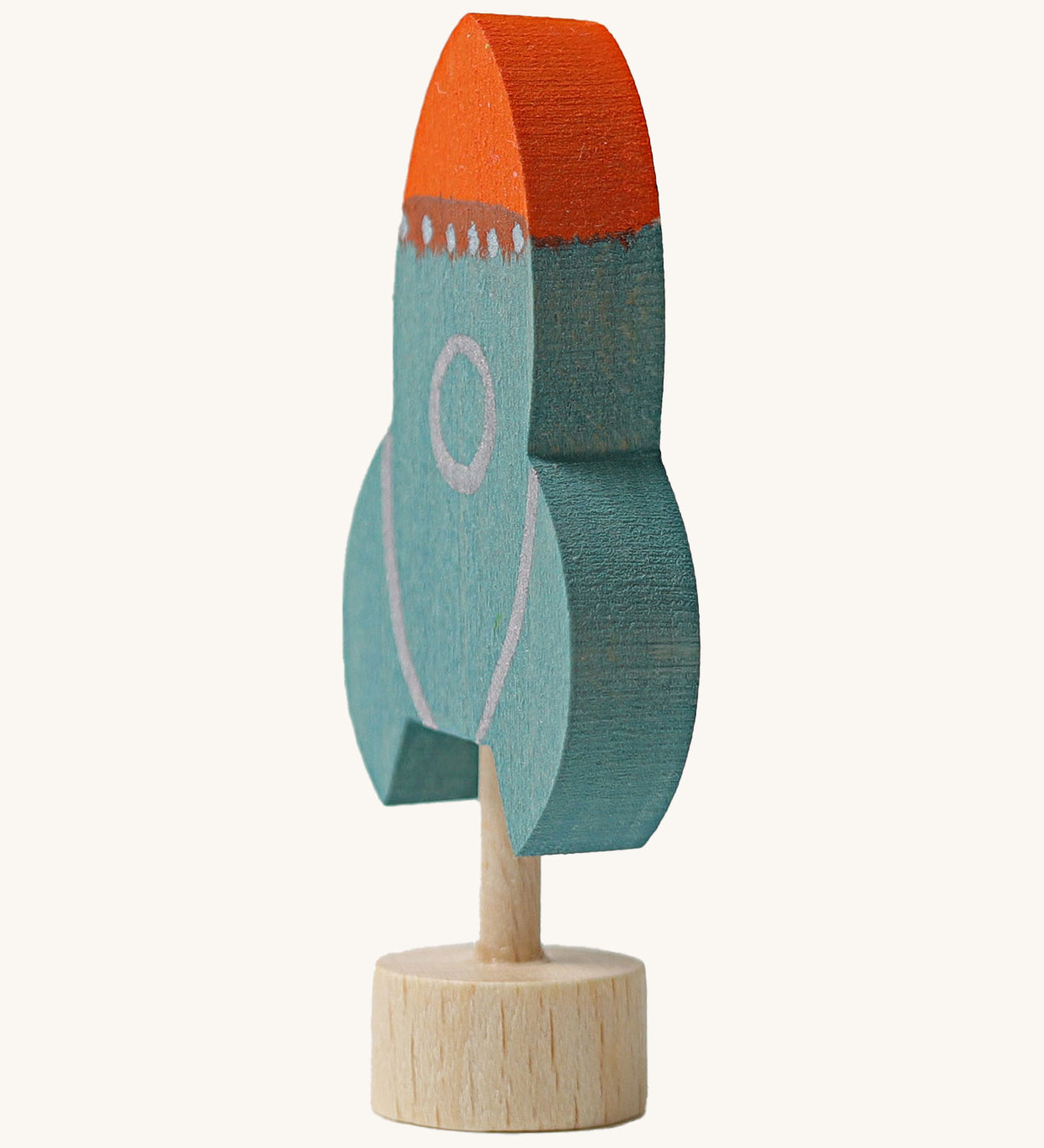 A side view of a Grimms blue wooden decorative figure with a red nose showing the thickness of the figure
