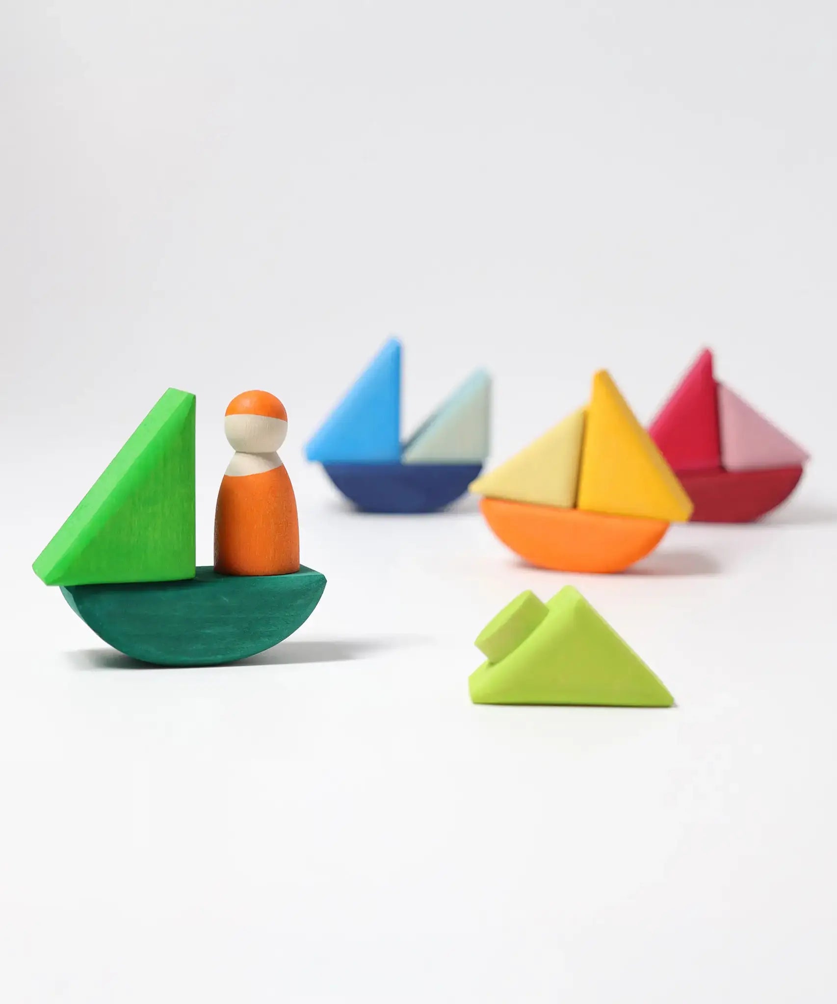 4 little sailboats made from the Grimms handcrafted wooden rolling boats pieces with a peg doll standing on one boat