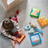 A child playing with the Grimm's Wooden Stacking Puzzles. All four puzzles in the collection are around the child. These Grimm's toys are part of a wide range of wooden toys available here at Babipur. 