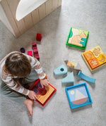 A child playing with the Grimm's Wooden Stacking Puzzles. All four puzzles in the collection are around the child. These Grimm's toys are part of a wide range of wooden toys available here at Babipur. 