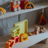 The blocks from the Grimm's yellow building set placed on a shelf with the yellow tray behind them. These Grimm's toys are part of a wide range of wooden toys available here at Babipur. 