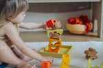A child playing with the yellow and natural wooden blocks from the Grimm's yellow building set. The child is stacking them on top of each other. These Grimm's toys are part of a wide range of wooden toys available here at Babipur. 