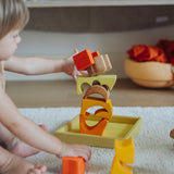 A child playing with the yellow and natural wooden blocks from the Grimm's yellow building set. The child is stacking them on top of each other. These Grimm's toys are part of a wide range of wooden toys available here at Babipur. 
