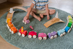 A child playing with the Grimm's Stacking Cars. Wooden toy cars that comes in a two back that can can be stacked on top of each other. The child has lined the cars up in a half circle shape.
These Grimm's toys are part of a wide range of wooden toys available here at Babipur. 