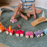 A child playing with the Grimm's Stacking Cars. Wooden toy cars that comes in a two back that can can be stacked on top of each other. The child has lined the cars up in a half circle shape.
These Grimm's toys are part of a wide range of wooden toys available here at Babipur. 