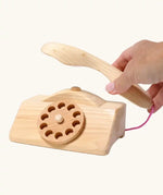 Grimm's wooden toy telephone. Adult's hand can be seen lifting the receiver off the base. 