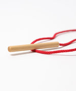 Grimms wooden threading needle showing needle detail with red cord attached