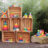 A display of different Grimms stacking and wooden toys standing inside crates in a garden