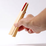 Adult hand holding the Grimms wooden 18cm tweezers  showing scale