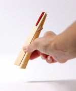 Adult hand holding the Grimms wooden 18cm tweezers  showing scale