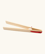 Grimms wooden 18cm tweezers held together by red elastic made to move small such as beads, marbles and small natural objects