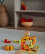 The yellow an natural wooden blocks from the Grimm's yellow building set stacked up on top of each other on the yellow tray. These Grimm's toys are part of a wide range of wooden toys available here at Babipur. 